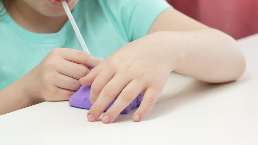 A little girl inflates a large bubble of purple slime through a cocktail tube. A fashionable liquid antistress toy sticks to his hands and fingers. Royalty-Free Stock Footage #3463167209
