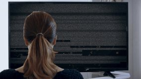 Watching TV Noise Interference Signal Video Glitch. Young woman watching big screen television with static noise. Shot behind model shoulders. - Powered by Shutterstock - Get 15% off with code: PIKWIZARD15