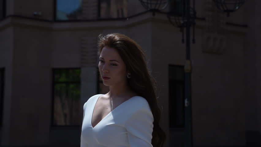 a woman in a white dress is walking down the street in front of a building
