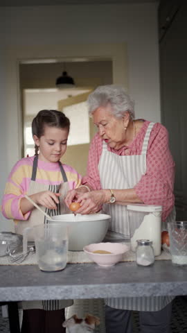 Grandmother with grandaughter preparing traditional easter meals, baking cakes and sweets. Passing down family recipes, custom and stories.