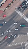 Aerial view of vehicles on city highway intersection. Traffic of cars and pedestrians. Vertical video.