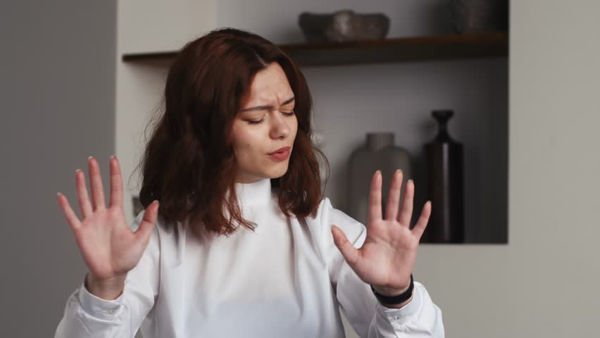Portrait displeased woman gesturing stop sign with hands at home . Closeup young model saying no on office background. Serious girl showing negative gesture at camera in slow motion. Displeased lady
