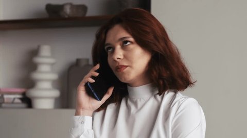 Closeup business woman talking friendly on cell phone at home or office. Portrait of pretty woman flirting on phone . Serious girl conversing in modern office in slow motion. Adlı Stok Video