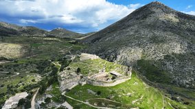 Aerial drone cinematic rotational video of uphill iconic archaeological site of Ancient citadel of Mycenae famous for round tomb of Agamemnon and Lion Gate, Argolida, Peloponnese, Greece