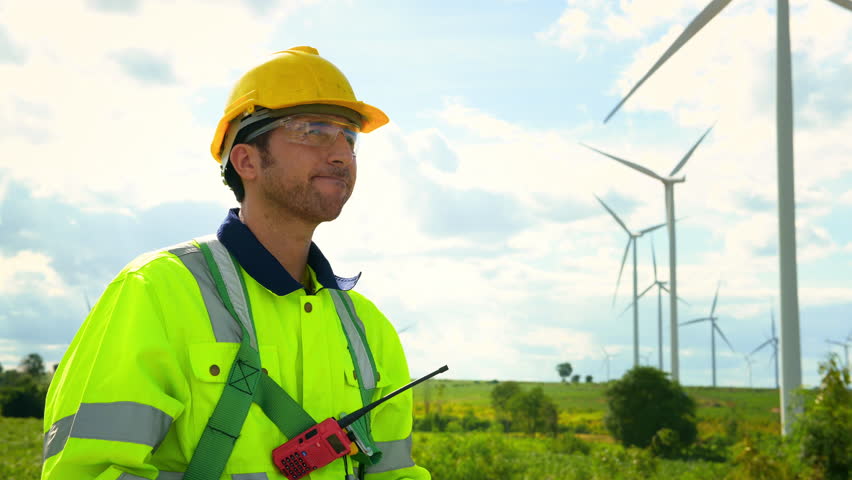 Smart engineer wearing protective helmet drinking water while working at electrical turbines field