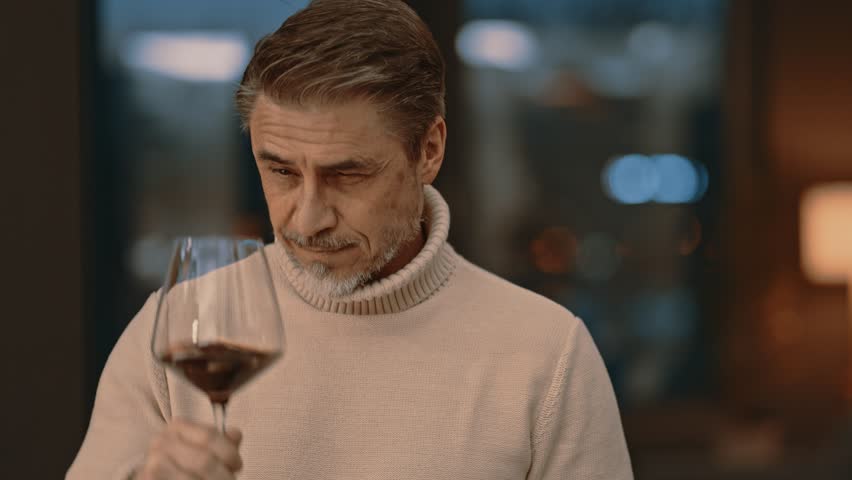 Mid adult man drinking, tasting wine at home in cosy room. Portrait of happy, satisfied middle aged man, smiling. Royalty-Free Stock Footage #3463316395
