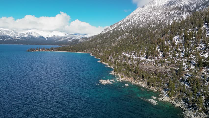 Aerial view of Lake Tahoe coastline with snow and mountains in the distance