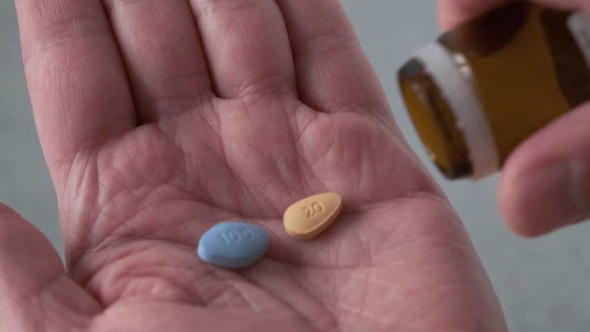 Man takes blue and brown pills in hand medication used to treat erectile dysfunction and prostatitis. Medication for erection. Close up