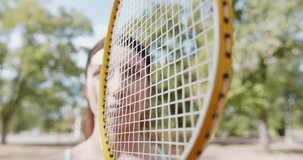 A close up video of a young sporty female holding tennis racket, ready for the game at an outdoor park or court.