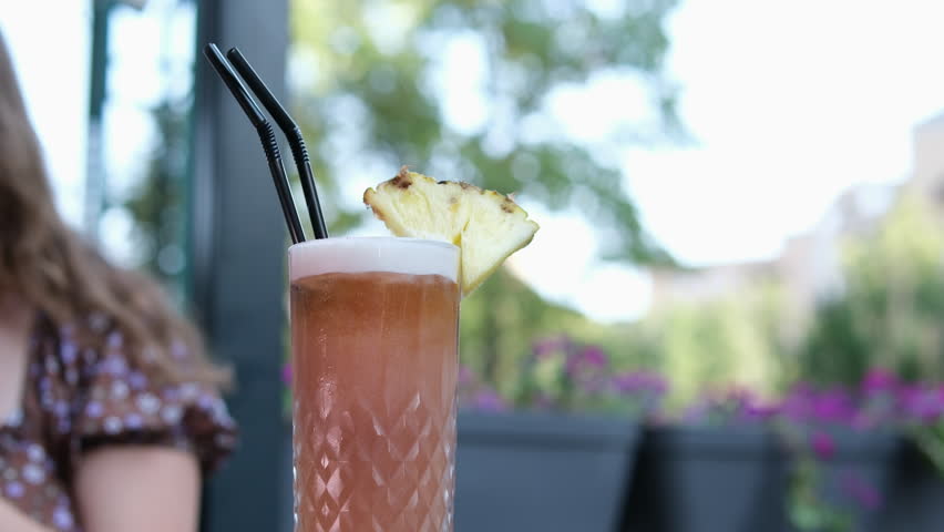 rotten, unappetizing mixing healthy organic juice using a drinking straw, enjoying her weekend outdoor, relaxing in a cozy cafe against unrecognizable blurrred people background