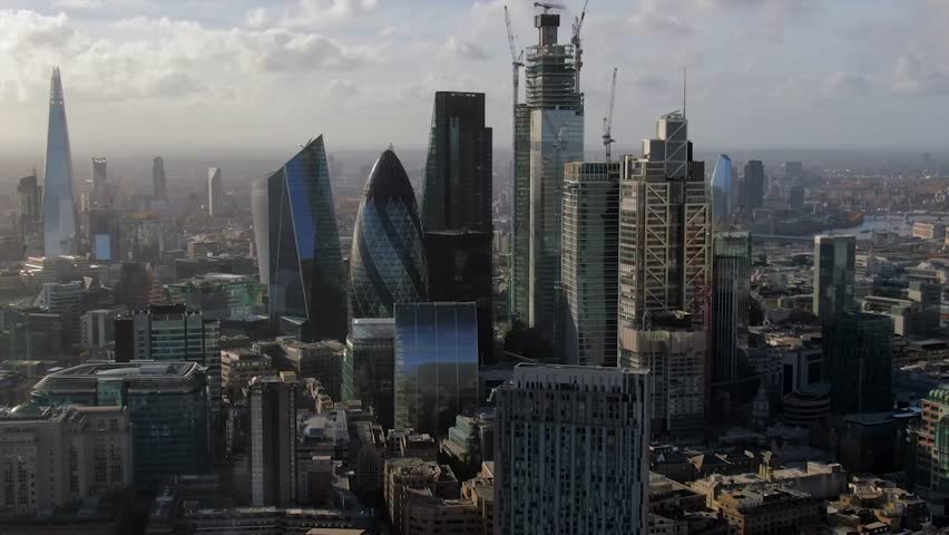 Aerial: Iconic London skyscrapers in cityscape, United Kingdom. A bird's-eye view of London's famous skyline, featuring its towering skyscrapers. Royalty-Free Stock Footage #3463499789