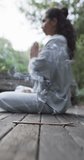Vertical video of focused biracial woman practicing yoga in sunny garden, slow motion. Lifestyle, wellbeing in nature, yoga, fitness, healthy lifestyle and domestic life, unaltered.
