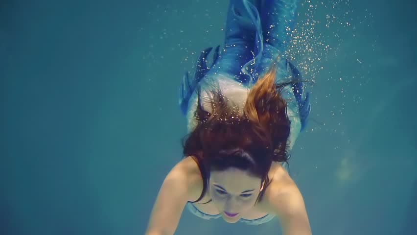 cute mermaid girl swims underwater in the blue ocean waters