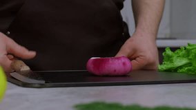 Slow motion video of a chef chopping onions. Close-up of a kitchen knife cutting an onion. The video follows the length of slicing onions. This vegetable contains a lot of vitamins.
