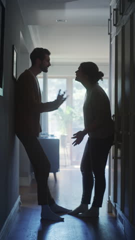 Vertical Video. Couple Arguing and Fighting. Domestic Violence Scene of Emotional abuse, Stressed Woman and aggressive Man Having Almost Violent Argument in a Dark Claustrophobic Hallway of Apartment Royalty-Free Stock Footage #3463610481