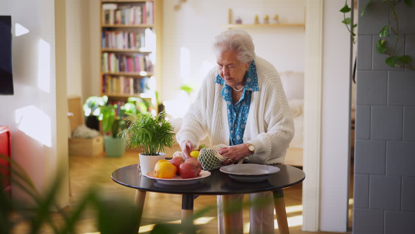 Elderly senior woman returning from shopping with a bag of apples.