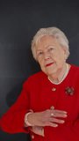 Video of elegant elderly woman with crown in red jacket looking at camera, smiling. Queen lookalike.