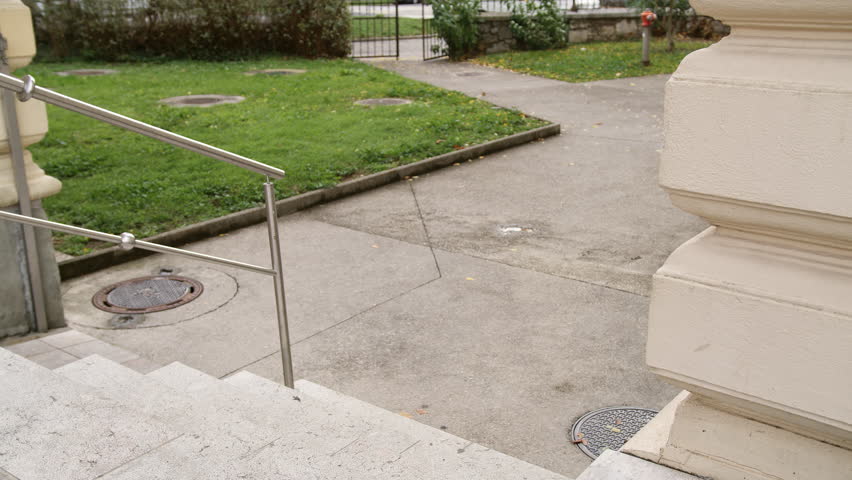 Guide dog helping his owner, a blind, namely visually impaired man, to go up the stairs, handheld shot. Seeing eye dogs and mobility aid concepts.