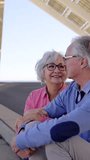 Slow motion video of a senior couple sitting in a viewpoint talking and enjoying views in the city