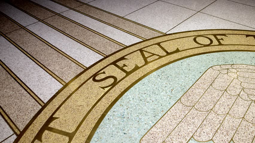 People walking near state seal on the floor inside New Mexico capitol building in Santa Fe, New Mexico with video panning right to left.