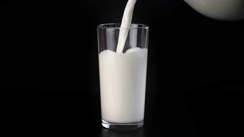 Pouring milk into glass, closeup view, isolated shot in black background, organic plant milk in jug. Healthy lifestyle and nutrition, food and drinks for breakfast, dinner or lunch, milk from eco farm