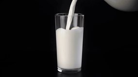 Pouring milk into glass, closeup view, isolated shot in black background, organic plant milk in jug. Healthy lifestyle and nutrition, food and drinks for breakfast, dinner or lunch, milk from eco farm - Powered by Shutterstock - Get 15% off with code: PIKWIZARD15