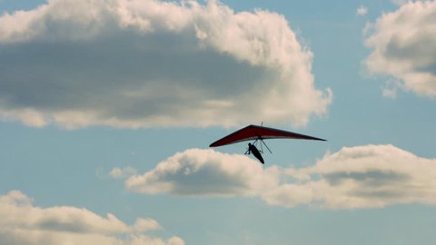 Hang glider being towed past puffy white clouds