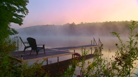 Nice Adirondack chairs on cottage dock overlooking foggy morning lake