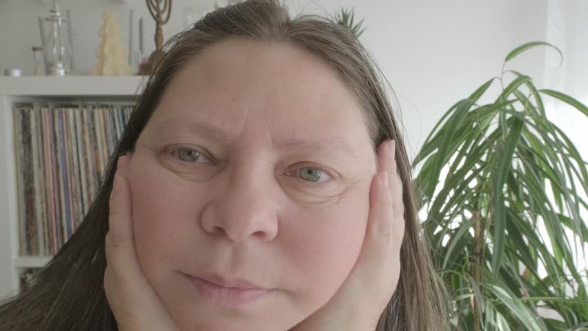 self-aware woman 50 years of age, takes moment to assess her facial features, particularly jowls, reflecting on natural process of aging and considering options for maintaining youthful appearance Royalty-Free Stock Footage #3463892399