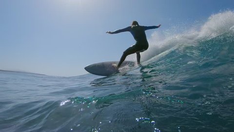 SLOW MOTION, LOW ANGLE, UNDERWATER: Surfer makes a turn on big blue ocean wave on hot sunny day in summer. Surfer carving awesome wave on his cool surfboard. Epic shot of male riding wave on surfboard