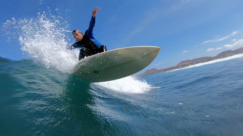SLOW MOTION: Surfer dude making a sharp turn on his surfboard and splashes water on camera lens. Sportsman having adrenaline fun carving dangerous ocean waves. Young surfer riding epic wave in the sun Stock Video
