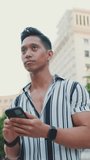 VERTICAL VIDEO: Close-up of young man tourist uses maps app on mobile phone