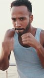 VERTICAL VIDEO: Close up, young bearded male fit athlete boxer practicing punching technique while standing on the embankment