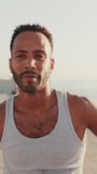 VERTICAL VIDEO: Close up bearded male fit athlete looking at camera while standing on the embankment