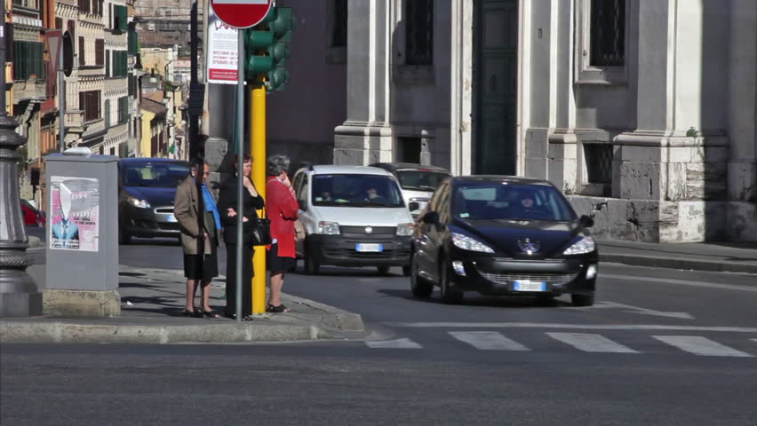 ROME - CIRCA MAY 2012: Two women wait for the traffic signal as cars pass by and