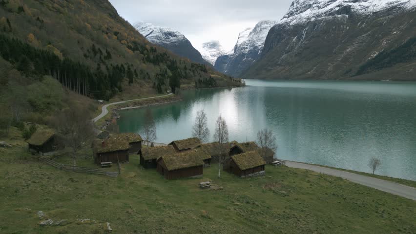 Tranquil Scandinavian landscape with traditional grass-roofed houses by Lovatnet Lake, Norway, autumn colors
