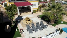 Aerial drone footage of a beautiful house in the town of Benidorm in Spain showing the two story Spanish house with a swimming pool on a hot day in the summer time