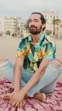 VERTICAL VIDEO: Young man relaxing on the beach