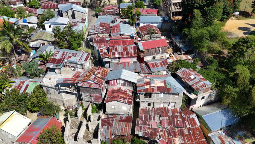 Dangerous slum neighborhood on Hill during Sunny day. Luxury Villa beside Favela. Hispaniola Island, Dominican Republic, Haiti. Aerial rising top down shot.  Royalty-Free Stock Footage #3464096375