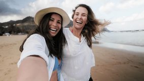 Gay women couple smiling at beach side during travel vacations. Happy lesbian taking selfie video together