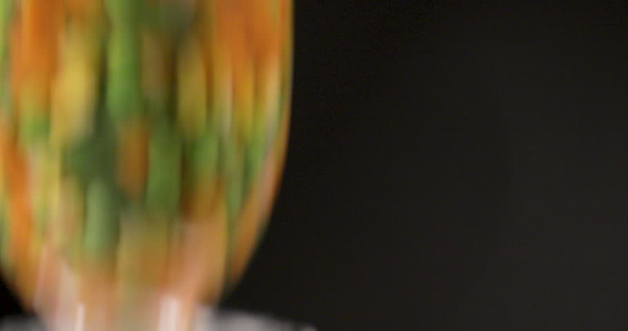 Mix of Fresh Vegetables dropped into water inside a glass with colorful combination with a black background and shot on 4K