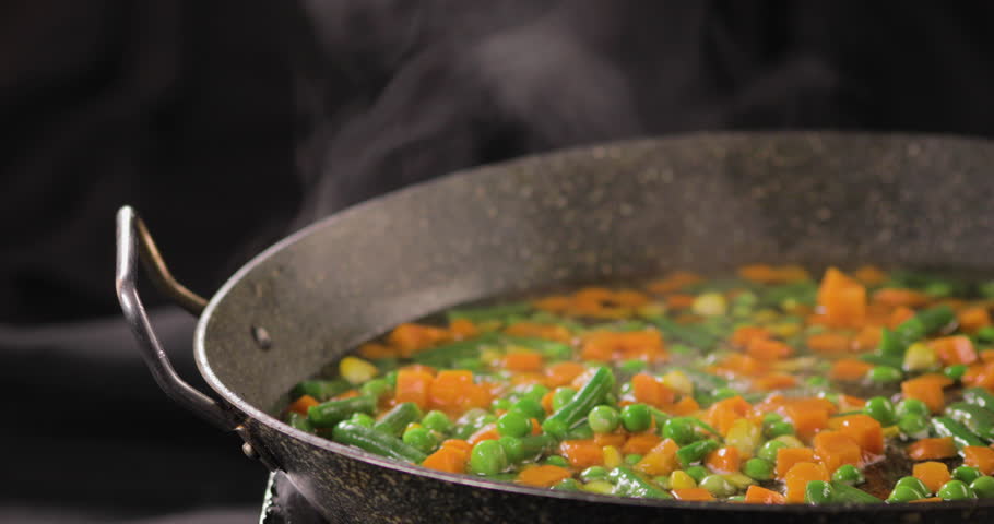 Mix of Fresh Vegetables in a cooking pan with colorful combination of Green peas and Carrots with a black background and shot on 4K