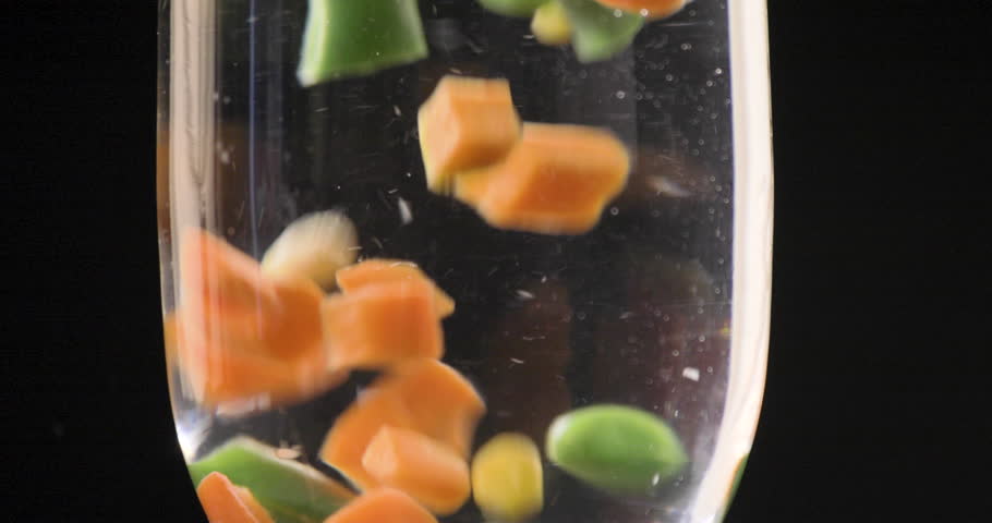 Mix of Fresh Vegetables dropped into water with colorful combination with a black background and shot on 4K