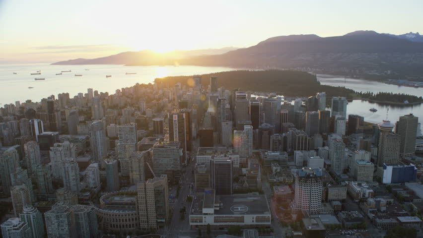 Vancouver Canada - Sept 2017: Aerial overhead view sunset over Vancouver city skyline skyscrapers and helipad Stanley Park Cypress Mountain ranges British Columbia Canada RED WEAPON