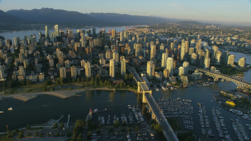 Aerial sunset view Vancouver cityscape from False Creek iconic landmark bridges and Grouse mountain ranges British Columbia Canada RED WEAPON