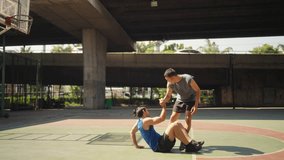 4K Caucasian man basketball player lifting fallen friend on outdoors court. Sportsman do sport training streetball at street court under city highway. Fair game competition and sportsmanship concept. - Powered by Shutterstock - Get 15% off with code: PIKWIZARD15
