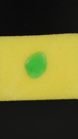I drip detergent on a yellow sponge, top view. Dolly slider extreme close-up inside. Vertical video.