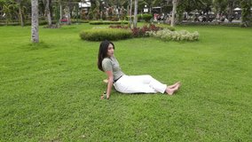 Aerial view of young Asian woman sitting down on a park enjoying the atmosphere and scenery