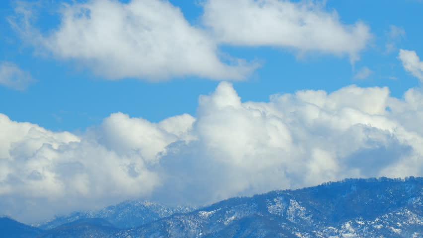 Mountains With Clouds Running Opposite Direction On Blue Sky. Snow-Covered Hills Of Mountains. Timelapse.