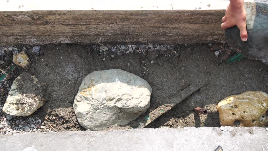 Construction, Worker Hands smooth wet cement in wooden frame at a construction site during daytime to ensure an even surface